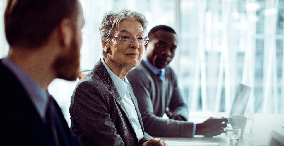 Two male and one older-looking female professional sitting at a desk