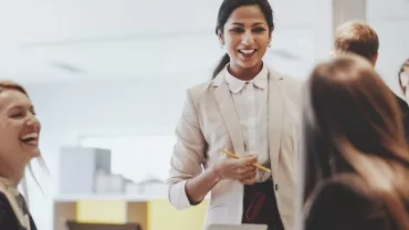 A woman leading a team meeting with smiling colleagues.