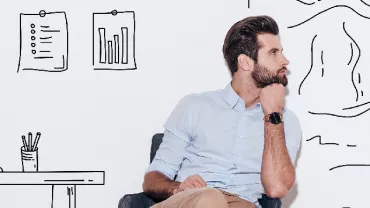 Man sitting and thinking in front of wall with drawings of graphs and landscapes.