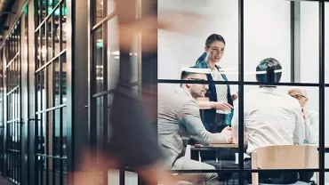 Colleagues in a modern office meeting room, engaged in discussion.