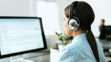 Person at computer wearing a headset, working in a call center.