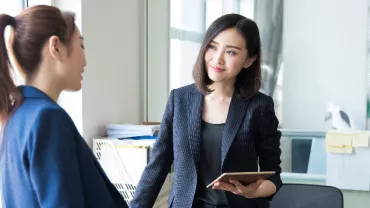 Two professionals having a discussion in a modern office setting.