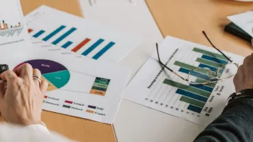 Two people reviewing financial charts and graphs at a desk.